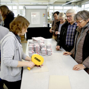 Janine Tremp befüllt die Jasskartenverpackung und klebt diese zusammen.